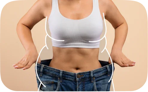 Person wearing oversized jeans and a white sports bra showing weight loss and body transformation